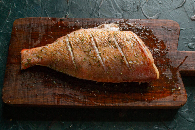 Seasoning the Fish Raw sea bass seasoned with herbs, salt, and fresh lemon juice