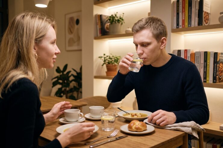 Support from loved ones and a calm atmosphere at the table A man drinks water while conversing with a woman during dinner in a cozy cafe.