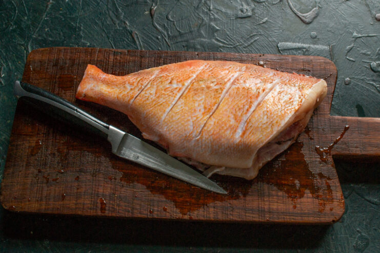 Scoring the Sea Bass Diagonal scores cut into the skin of a raw sea bass
