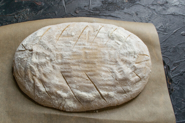 Scoring the dough Diagonal cuts being made on the surface of the bread dough