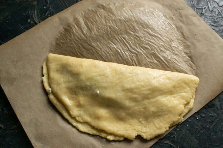 Shaping The Pie Folding the empty half of the dough over the filling using parchment paper