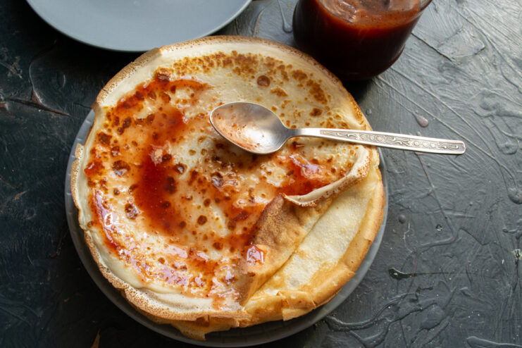 Spreading fruit jam over a thin crepe