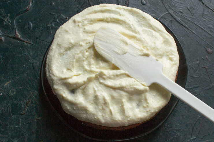 Assembling The Nut Cake Spreading thick white frosting over a baked nut cake
