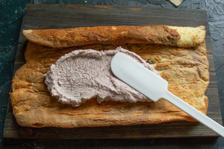 Filling the roll Spooning pink cream onto the unrolled marble sponge cake