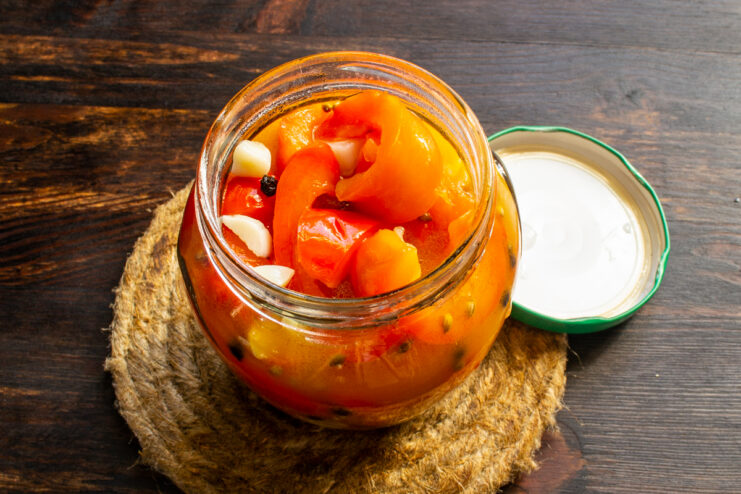 Packing the peppers into jars Filling a glass jar with hot pickled peppers and boiling marinade