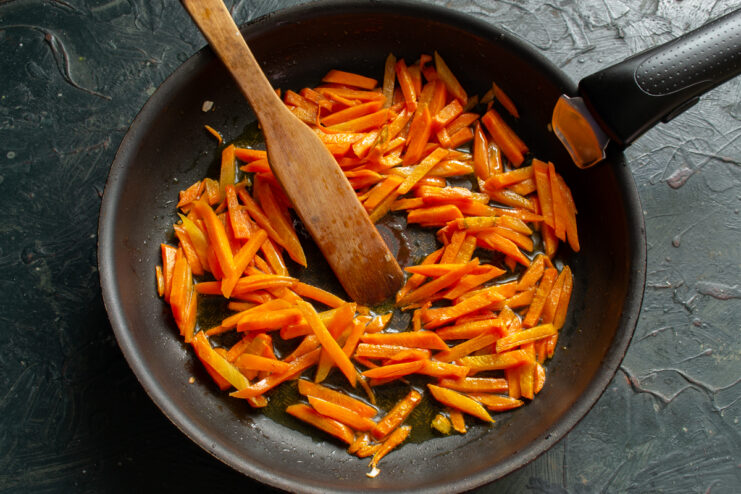 Sautéing thick carrot matchsticks in oil in a frying pan