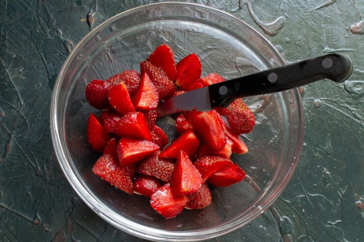 Slicing Strawberries For The Salad Sliced strawberries gathered in a glass bowl