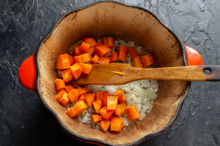 Adding carrots to the pot Large diced carrots added to onions