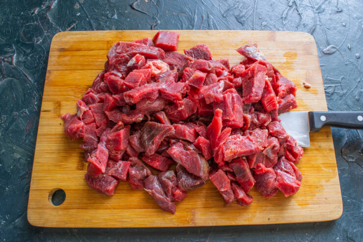 Prepping The Beef Cut pieces of lean beef on a wooden cutting board