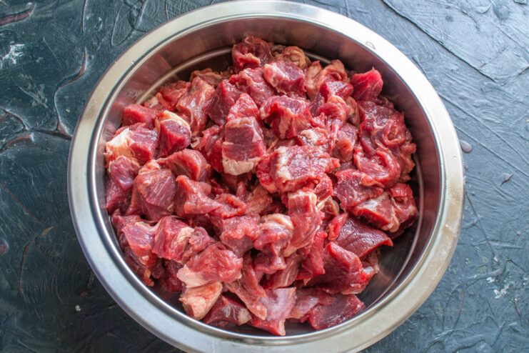 Preparing the beef Raw beef cut into small pieces in a stainless steel bowl