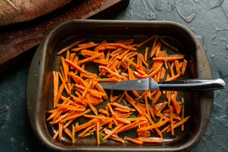 Preparing the Vegetable Base Julienned carrots spread evenly across the bottom of a baking dish