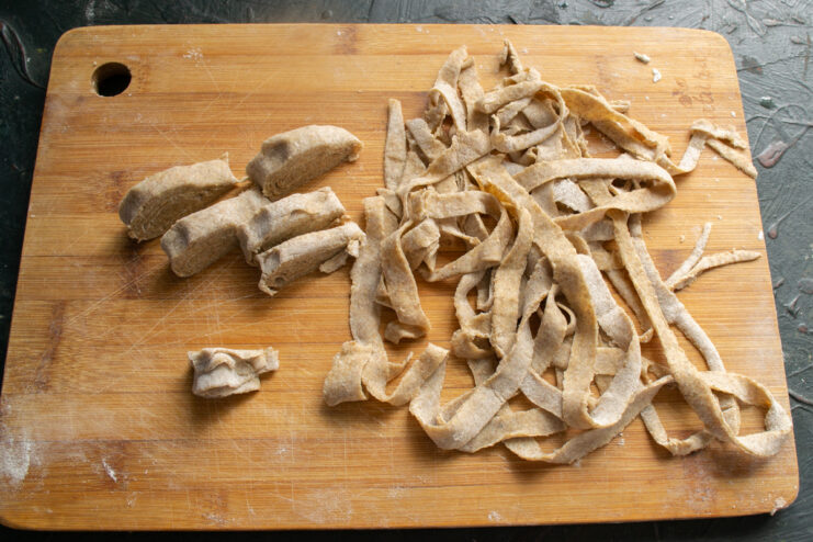Slicing the rolled dough Slicing a cylinder of rye dough into strips to form long homemade noodles