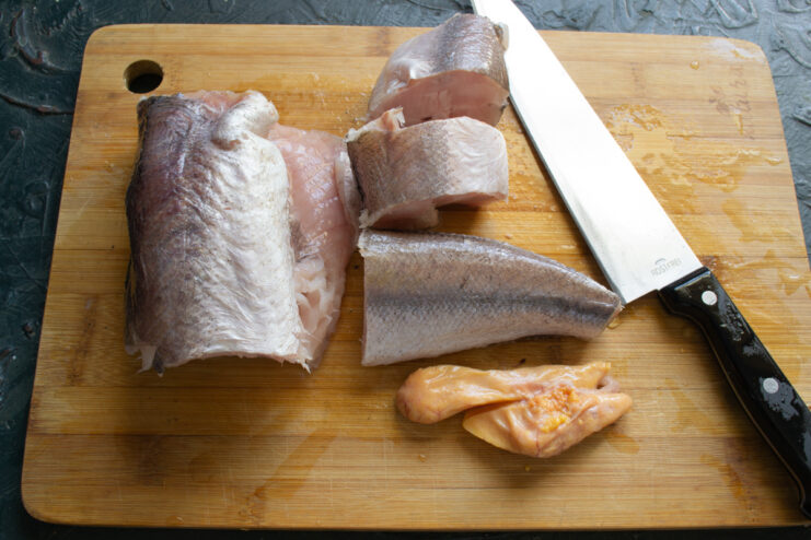 Prepping the Fish Cut hake pieces and fish roe resting on a wooden cutting board.