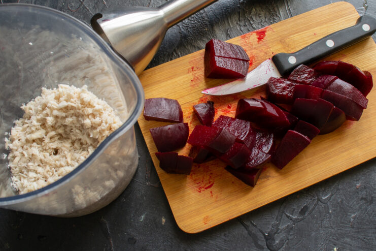 Adding Beets To The Sauce Diced boiled beets and grated horseradish on a cutting board