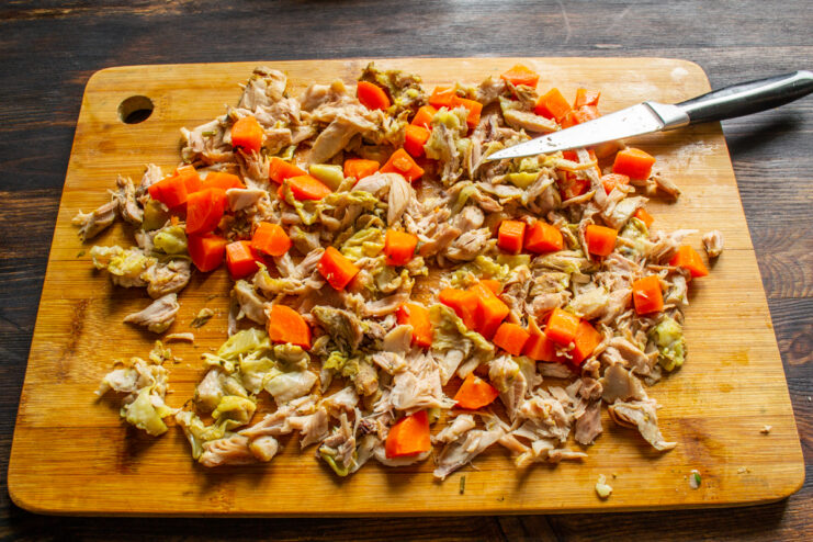 Preparing The Filling Shredded cooked chicken meat and diced carrot on a board