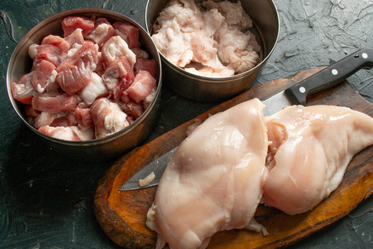 Preparing meat for homemade mince Cubed raw pork, chicken fillet, and pork fatback in metal bowls