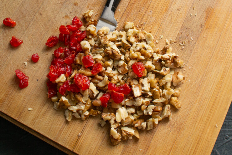 Preparing nuts and berries Chopped walnuts and dried cranberries piled on a wooden cutting board
