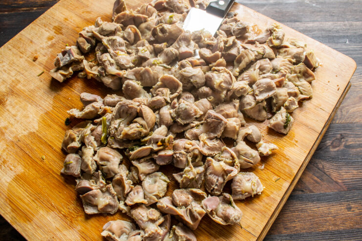Chopping cooked gizzards Chopped boiled chicken gizzards on a wooden cutting board