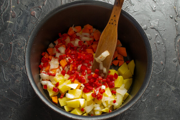 Adding sweet bell pepper Diced red bell pepper added to the pot with other vegetables