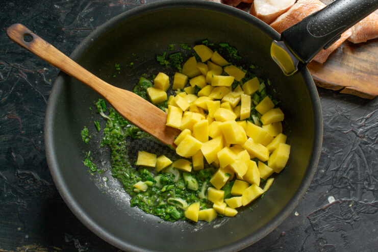 Adding the Potatoes Diced potatoes added to a pot with sautéed herbs