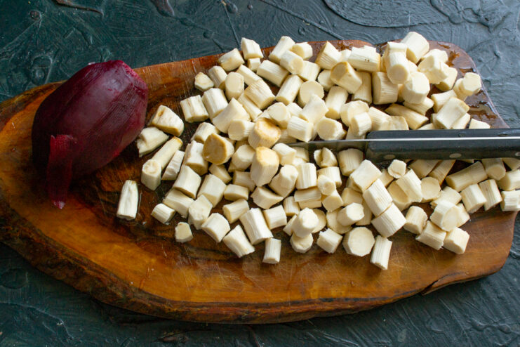 Dicing horseradish and boiling beet Diced horseradish roots and a whole boiled beet on a wooden cutting board.