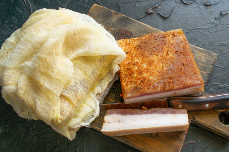 Final maturation stage Slicing the finished red-crusted Hungarian-style salo after removing the cheesecloth