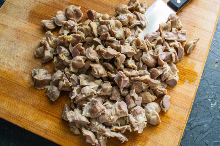Chopping ingredients for sautéing Chopping boiled gizzards on a wooden cutting board