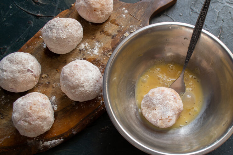 Dipping a floured fish meatball into beaten egg