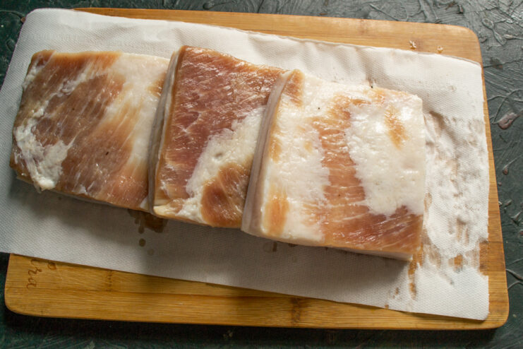 Drying the salo Patting the cured pork fat dry with paper towels on a cutting board