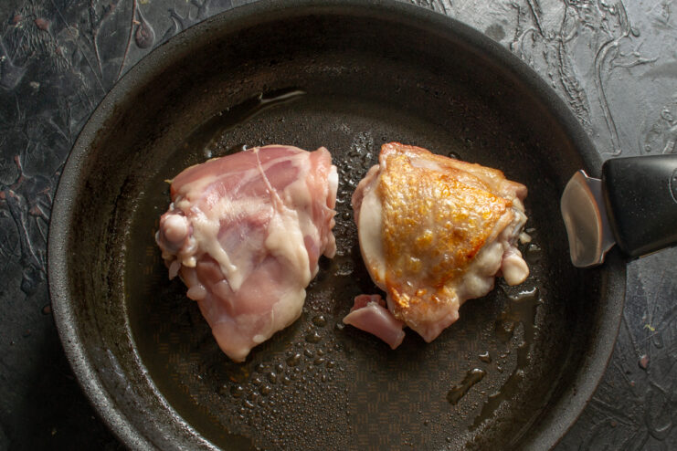 Preparing chicken for plov Searing chicken thighs in a skillet until golden brown