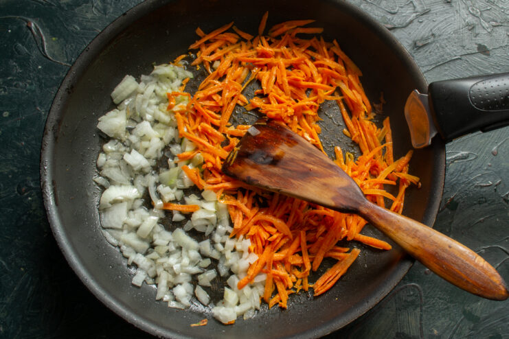 Sauteing the vegetables Chopped onion and grated carrots sauteing in a pan