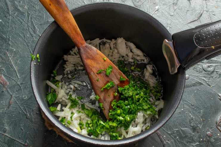 Sautéing the vegetables Sautéing finely chopped onions and parsley in a pot