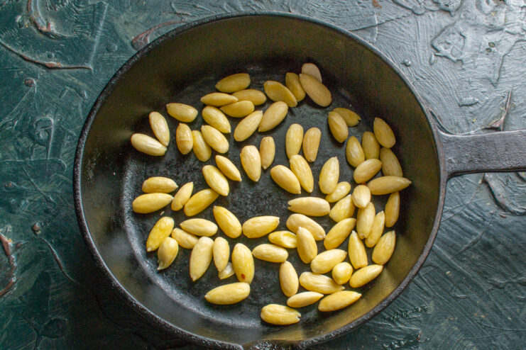 Peeled white almonds toasting in a dry skillet