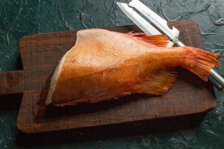 Cleaning the Fish Cleaned and gutted sea bass resting on a wooden cutting board