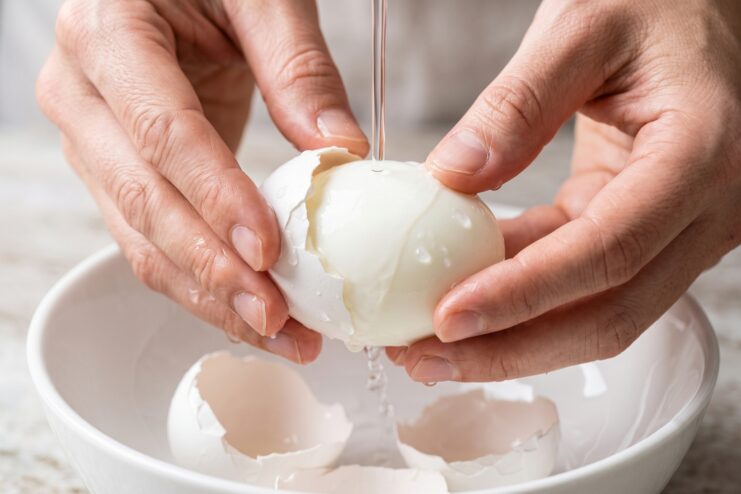 Peeling a Boiled Egg Under Water Peeling a boiled egg under a gentle stream of running water over a white bowl.