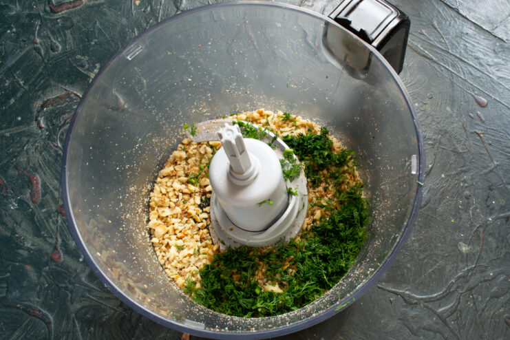 Adding herbs to walnuts Ground walnuts mixed with freshly chopped dill in a blender bowl