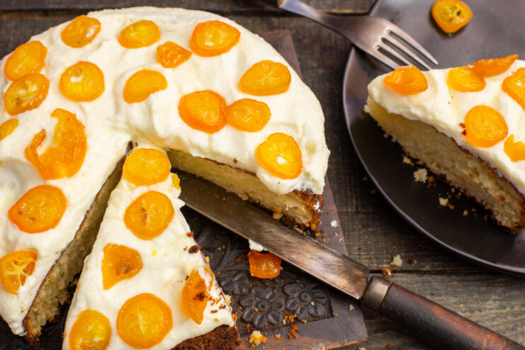 Finished nut cake frosted with mascarpone and topped with candied kumquats