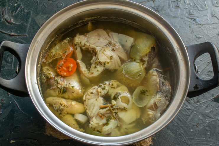 Simmering Fish Stock Boiled fish simmering in a clear broth with vegetables inside a pot.