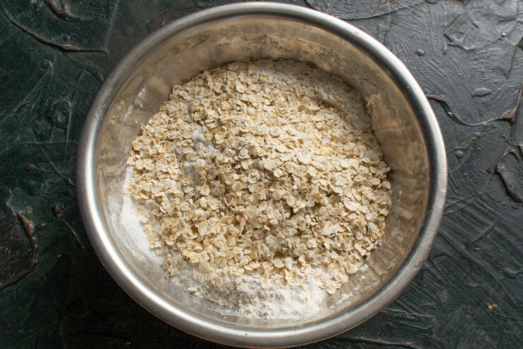 Adding quick oats Quick oats added to the dry flour and spice mixture in a bowl