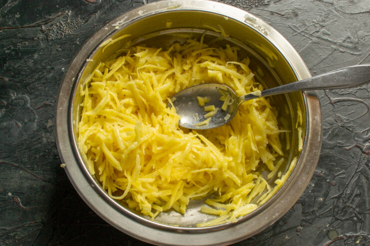 Mixing potatoes and eggs Stirring grated potatoes and eggs together with a spoon