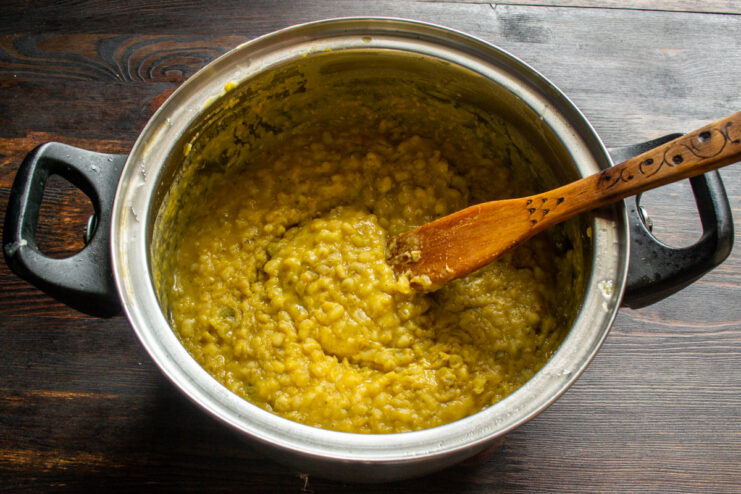 Stirring the finished thick porridge with pickles in a heavy pot