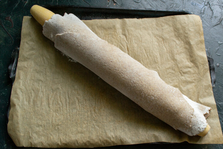 Prepping for baking Transferring a thin sheet of rolled dough onto a baking sheet using a rolling pin