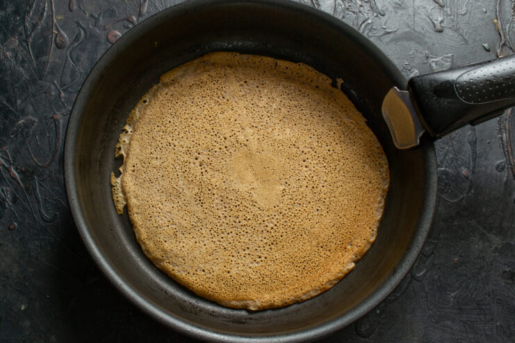 Flipping the crepe to cook the second side Flipping a cooked chocolate crepe to finish the other side
