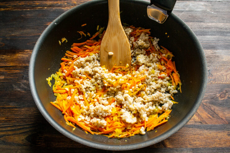 Mixing grains and vegetables Adding pearl barley to sauteed vegetables in a pan