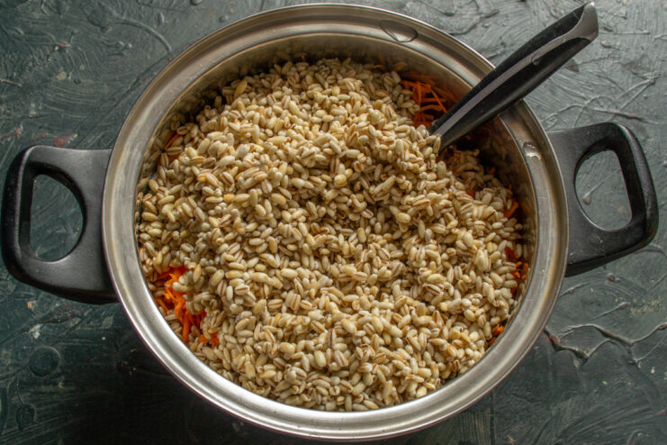 Adding pearl barley Pearl barley added to the pot with pork and vegetables