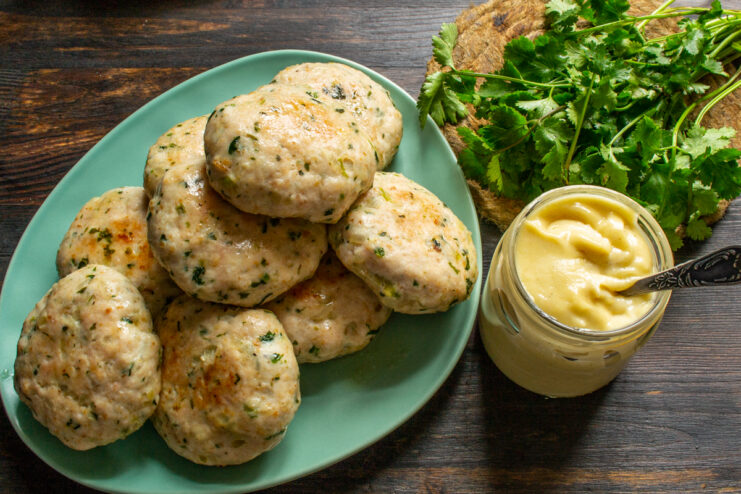 Serving the dish Plated chicken patties garnished with fresh herbs and sauce