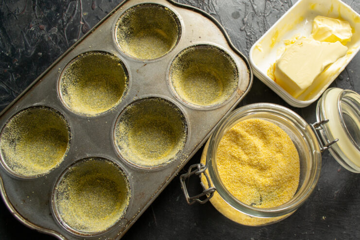 Preparing the muffin tin Greasing a muffin tin and dusting it with polenta for a crispy crust