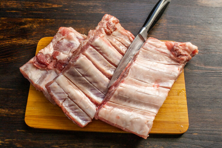 Preparing and scoring the pork ribs Removing the membrane and scoring pork ribs with a sharp knife on a cutting board.