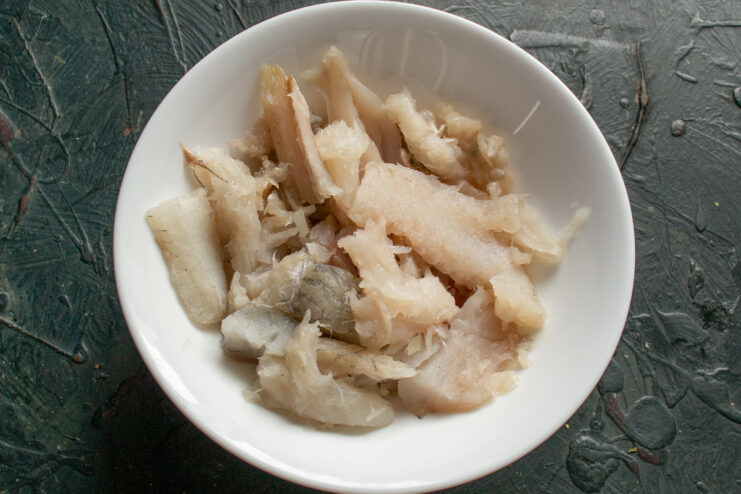Preparing the Fish Fillet Prepared saffron cod fillets cut into small pieces in a white bowl.