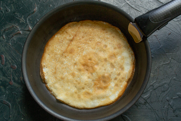 Cooking crepes until golden brown Frying a thin golden crepe in a hot skillet